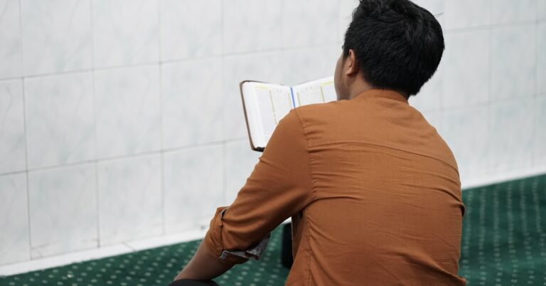 Um homem sentado em uma cadeira lendo um livro.