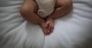 Descrição: um bebê deitado em cima de um travesseiro branco