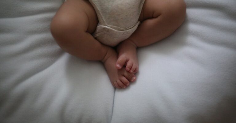 Descrição: um bebê deitado em cima de um travesseiro branco