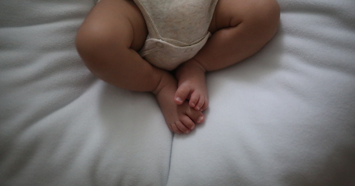 Descrição: um bebê deitado em cima de um travesseiro branco