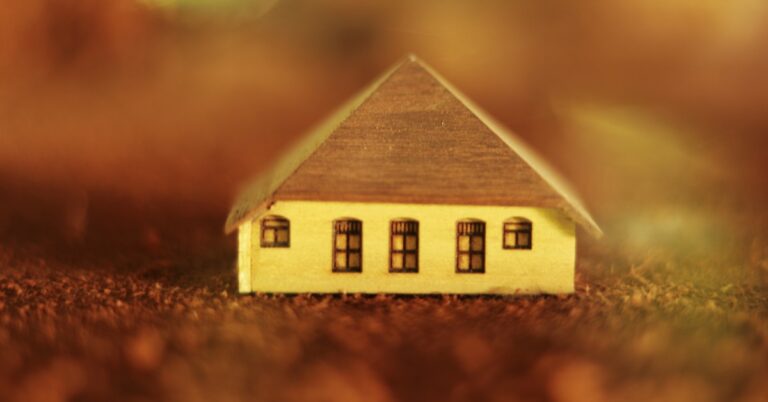 Descrição: miniatura de casa de madeira marrom em solo marrom