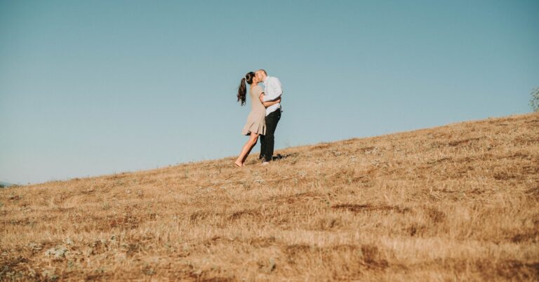 Mulher de camisa branca de manga comprida e calças pretas correndo em um campo de grama marrom durante o dia