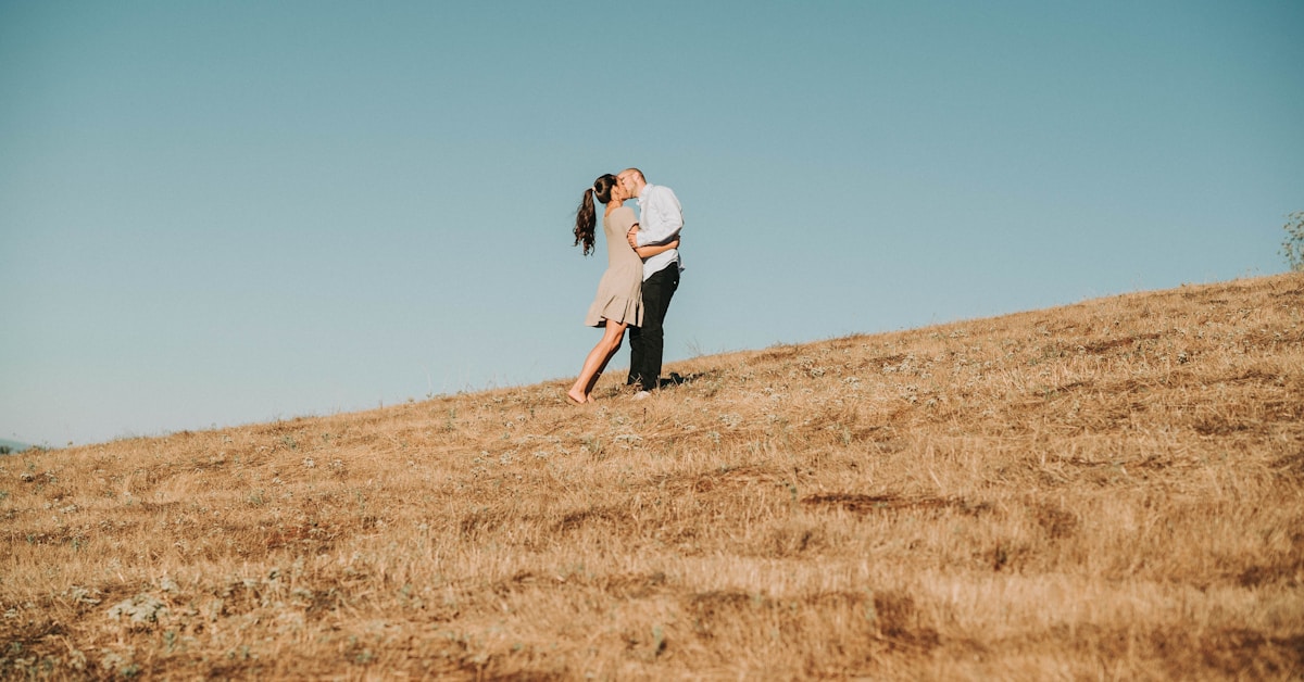 Mulher de camisa branca de manga comprida e calças pretas correndo em um campo de grama marrom durante o dia