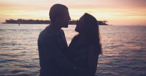 um homem e uma mulher em pé um ao lado do outro perto do oceano