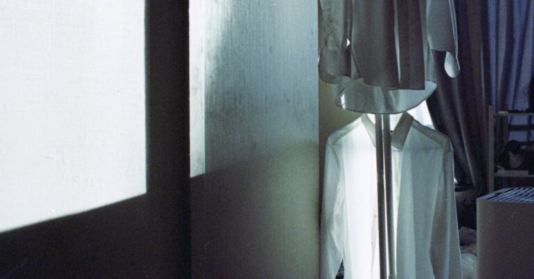Camisas brancas penduradas em um quarto mal iluminado
