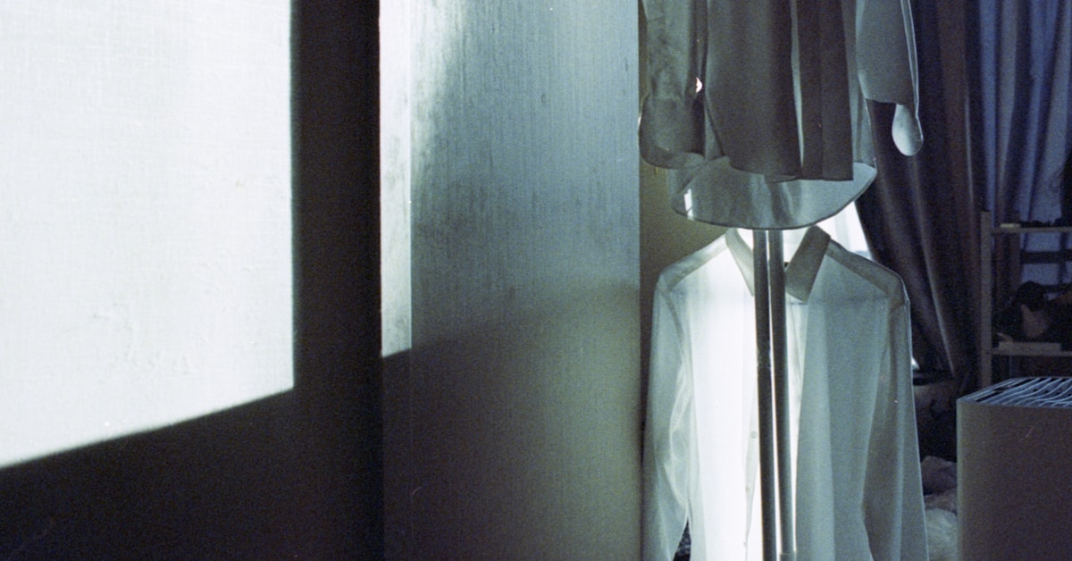 Camisas brancas penduradas em um quarto mal iluminado