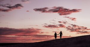 duas pessoas de mãos dadas enquanto estão em pé em uma colina
